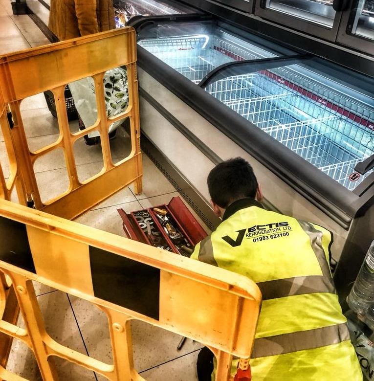 Vectis Refrigeration employee carrying out maintenance on a supermarket freezer